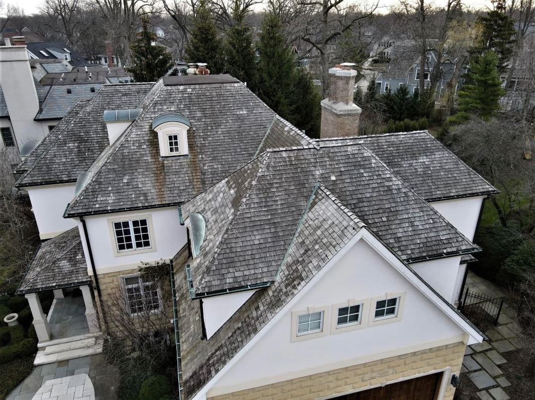 Aerial view of a stylish home with a slate roof and landscaped yard.