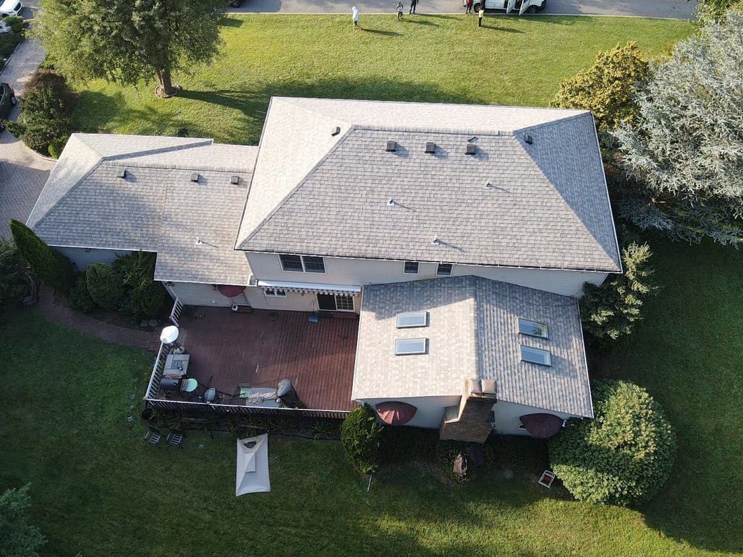 Aerial view of a modern house with a large deck and green lawn.